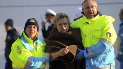 Rescue workers help a woman passenger