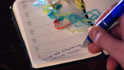 Person writing new year resolutions for 2012 in a diary