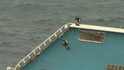 Rescue workers climb the ship using ropes