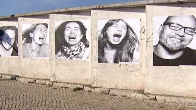 Posters of smiling people on a wall in Lisbon