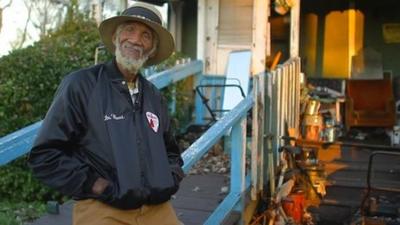 Bluesman Dr Burt stands in front of porch