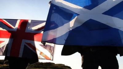 People hold up the Great Britain and Scottish flags