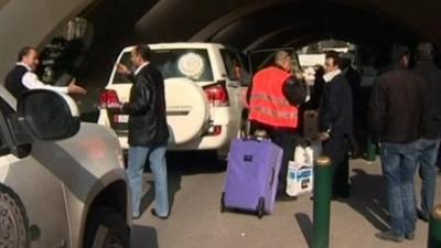 Arab League observers' luggage is wheeled into airport.