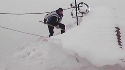 Man digging snow from roof