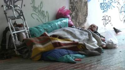 Homeless older man sleeps rough on the streets of Athens.