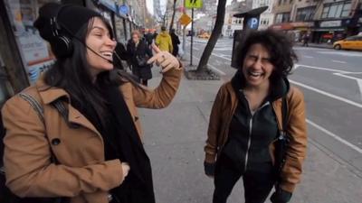 Two comedian standing and laughing on a sidewalk