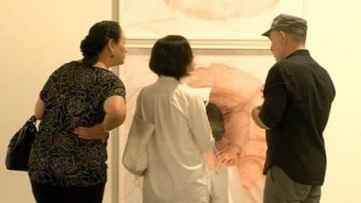 Visitors look at a painting at a Singapore art show