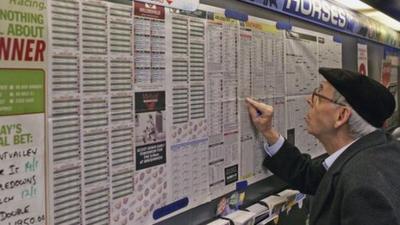 Man looking at horses in a betting shop