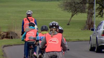 Adult cyclist leading 4 young cyclists on a road