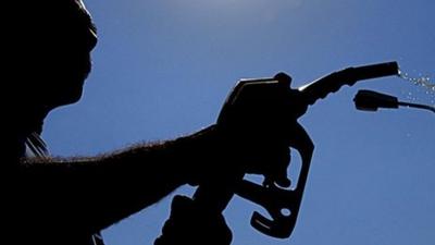 A silhouette of a man holding a fuel pump