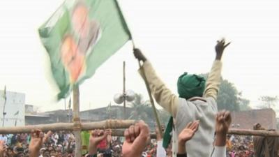 Man waving flag featuring the face of Mukhtar Ansari, a candidate for election who is in jail facing charges including murder