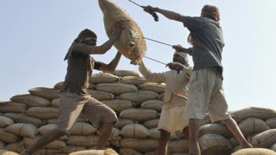 Indian workers lift a sack of rice to ship to a wholesale market