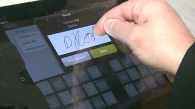A customer signing an iPad screen to pay for goods