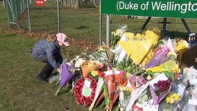 A child lays a tribute outside barracks