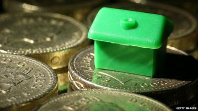 monopoly house resting on pound coins