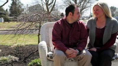 Young Levittown couple sitting on bench