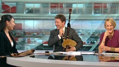 The BBC's Charlie Stayt tries to play the bagpipes
