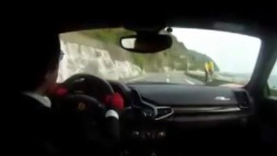 A man in red gloves drives a Ferrari in a video posted on YouTube