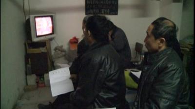 Chinese man and woman watch television set