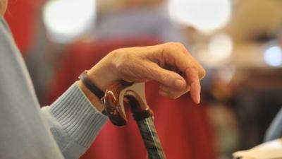 Elderly person resting on cane