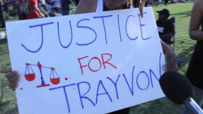 Woman holds sign that reads "Justice for Trayvon".