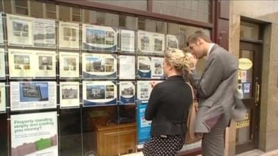 First time-buyers look at properties in the estate agent window.