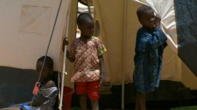 Child refugees, who have fled Mali to Niger with their family, stand outside a tent.