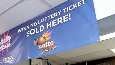 Banner in shop which says "winning lottery ticket sold here".