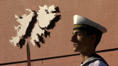 Argentine sailor in front of map of Falkland Islands