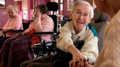 Woman in wheelchair reaches out to a friend