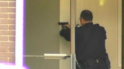 A police officer aims his handgun after a gunman entered a private Christian college in Oakland, California