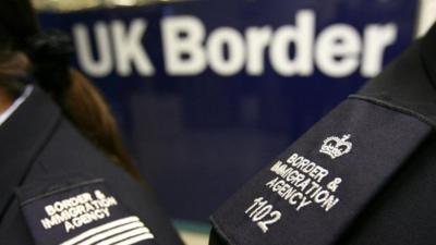 Border Agency officers standing in front of the UK Border sign