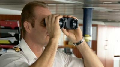 Crew of ship look through binoculars