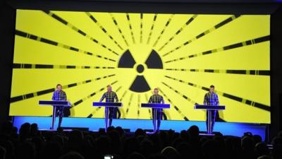 The band Kraftwerk performs in front of an atomic radiation symbol