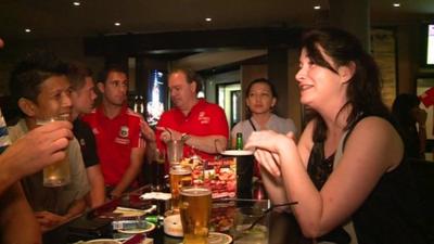 British football fans are among people drinking on a Saturday night in a Jakarta bar.