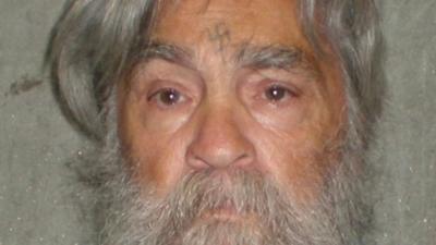 Close up of Charles Manson's face as an older man - with swastika he engraved on his forehead visible.