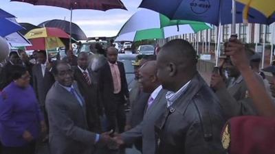 Robert Mugabe shaking hands with officials at Harare International Airport