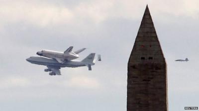 Space shuttle Discovery piggy-back on a 747, flying past the Washington Monument