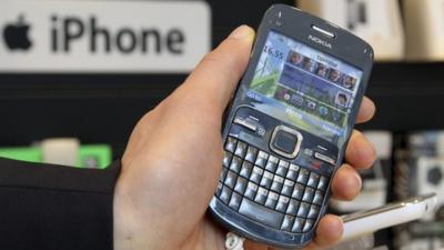 A Nokia mobile phone is pictured near an iPhone logo in a shop in Brussels.