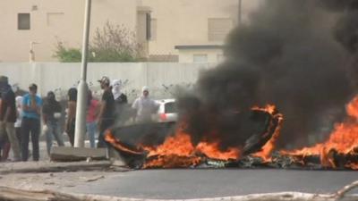 Protesters stand near fire in street in Bahrain