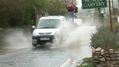 Car drives through water on road