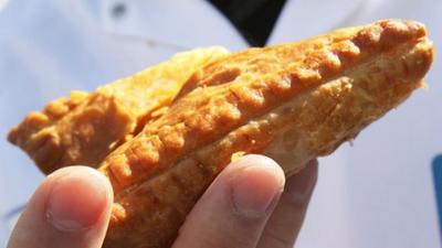 Greggs employer holding a pasty