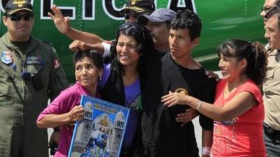 Injured police officer Luis Astuquillca stands next to his mother Fidela Vasquez (r) and other relatives as he arrives at Lima airport April 30, 2012