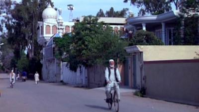 A man rides a bicycle along a road in Peshawar