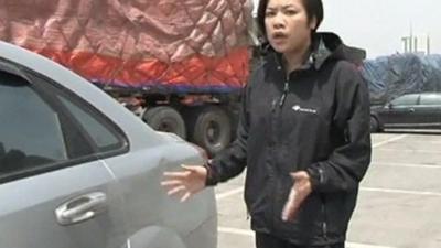 Reporter from Hong Kong Cable TV shows damage on a car