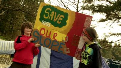 Children hold up 'Save Our Slope' sign