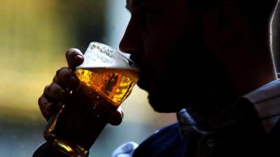 A young man drinking a pint of lager