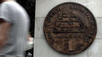 Men walk past depiction of the former Greek currency, the drachma