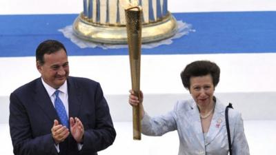 Princess Anne, Princess Royal (R) holds aloft the Olympic flame