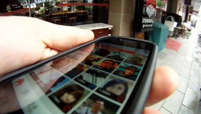 The BBC's John Sudworth holds an iPhone displaying an app.